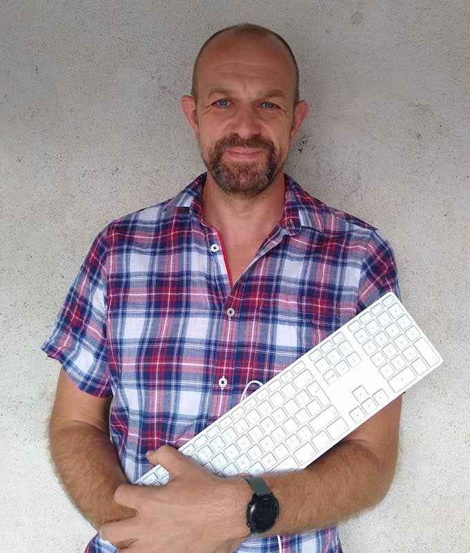 Fast Solutions - Een man in een geruit overhemd die een computertoetsenbord vasthoudt terwijl hij aan webshopmarketing werkt.