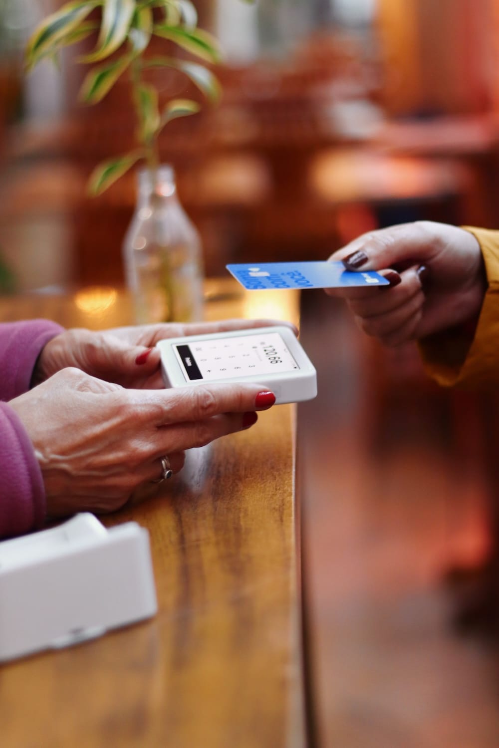 Fast Solutions - Een vrouw overhandigt een creditcard aan iemand anders aan een tafel, wat een transactie op het gebied van marketing illustreert.